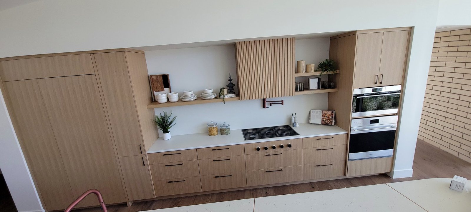 Contemporary kitchen built-in cabinetry with light wood grain and integrated appliances