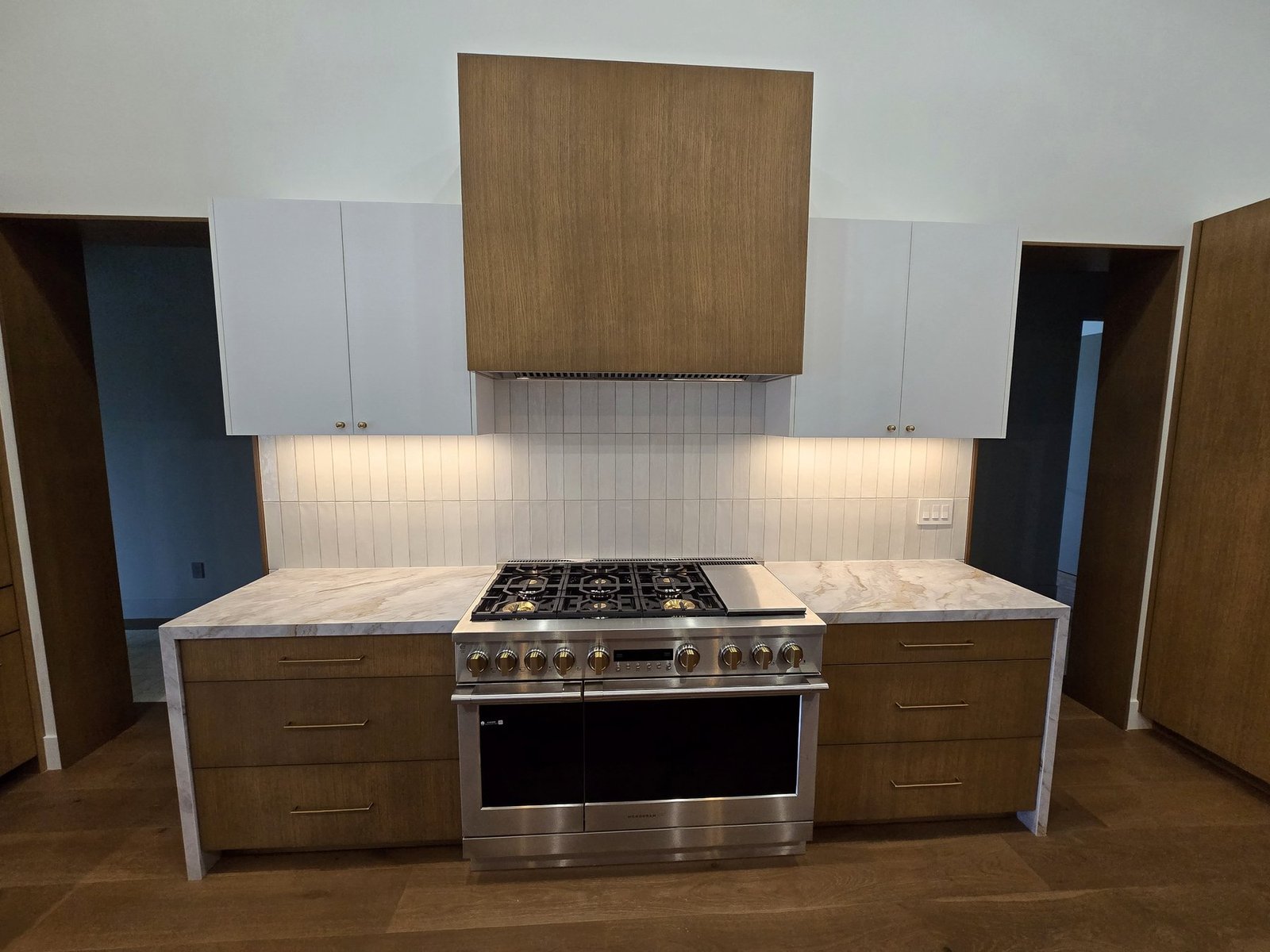 Custom kitchen range wall cabinet installation with white and walnut cabinetry