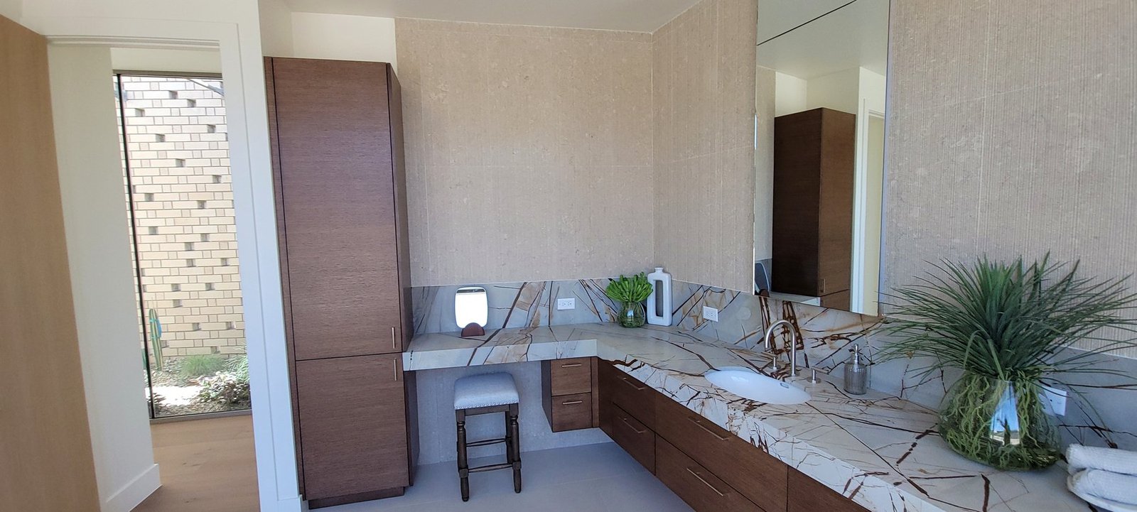 Floating vanity cabinet installation with warm wood cabinetry and dramatic stone countertop
