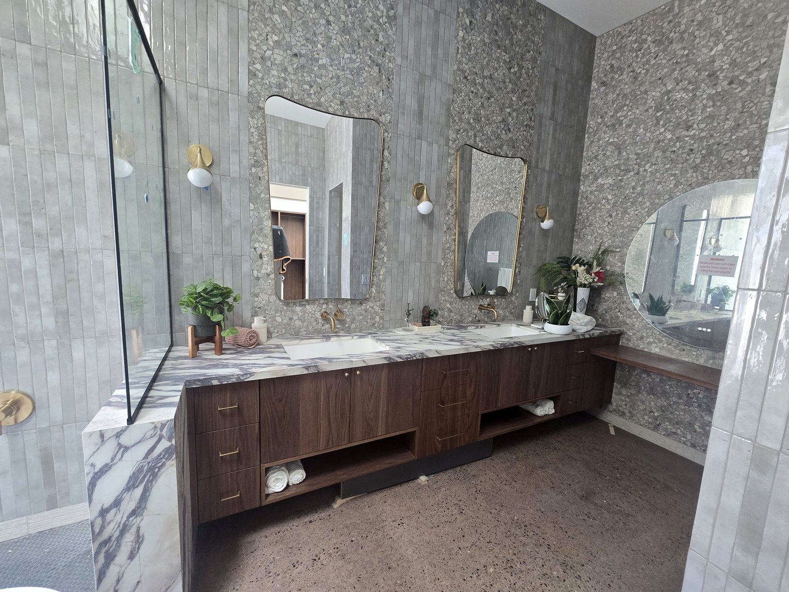 Luxury bathroom vanity installation with dual mirrors, marble counters and dark wood cabinetry