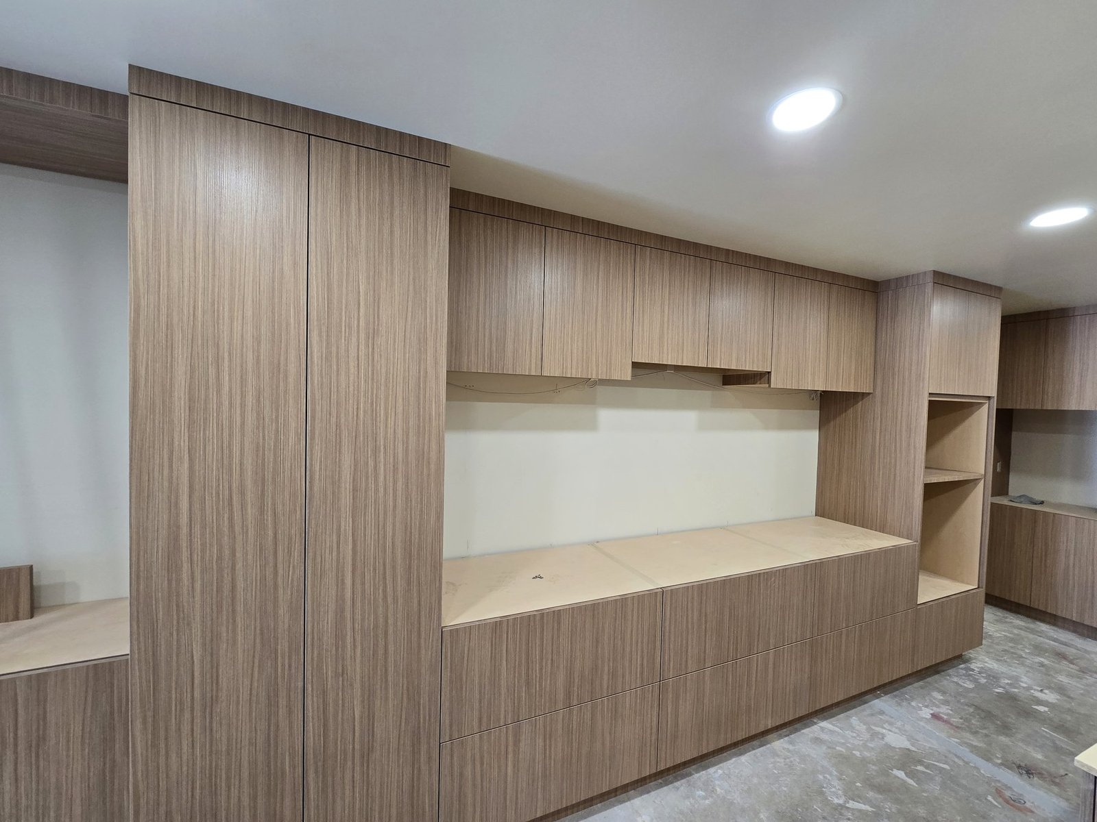 Media wall built-in installation with tall vertical grain cabinetry and drawers